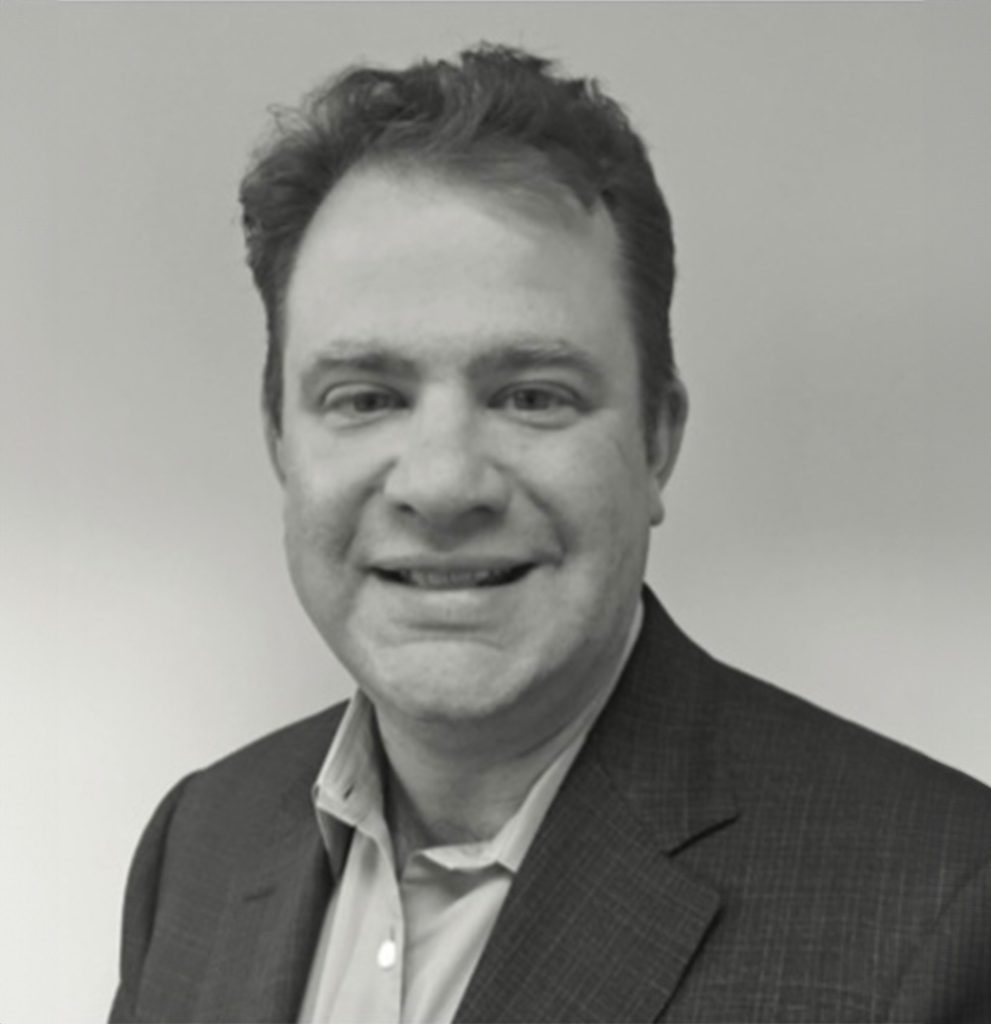 Man in a suit smiling in a grayscale photograph.